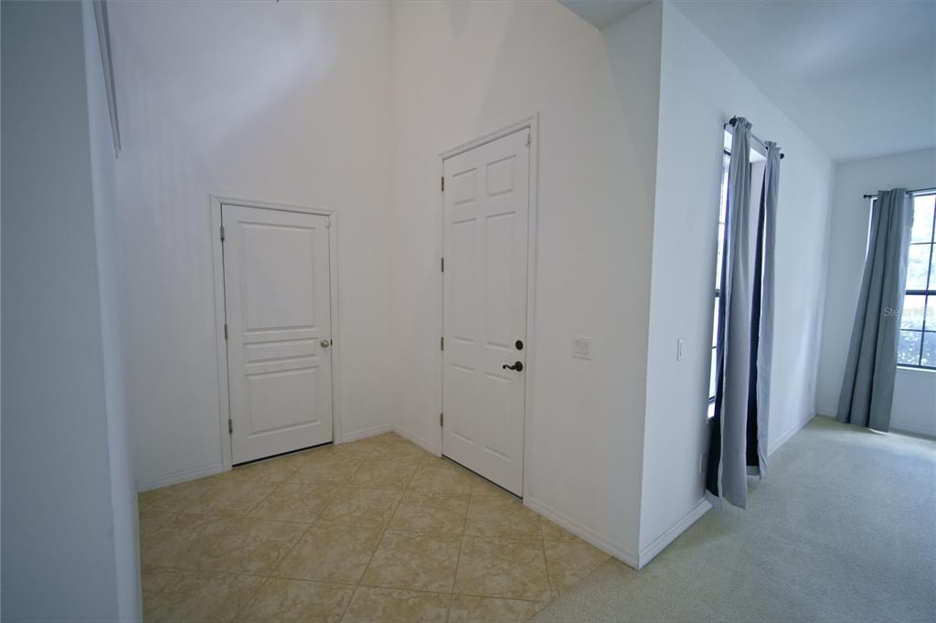 An entryway with tiled flooring, two white doors, and a carpeted room with windows — 3087 POINTE PLACE AVENUE, KISSIMMEE, FL