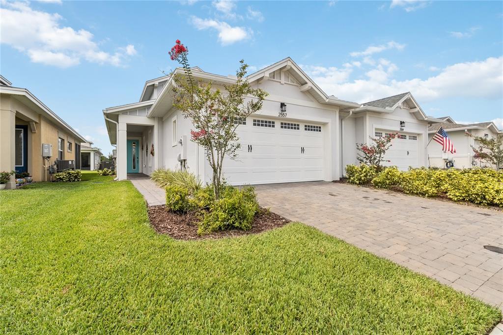 A single-story house with a white garage, paved driveway, and a small front yard — 2557 YELLOW BRICK ROAD, ST CLOUD, FL