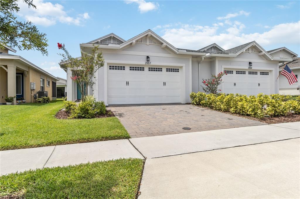 A view of two attached single-story houses with white garages and paved driveways — 2557 YELLOW BRICK ROAD, ST CLOUD, FL