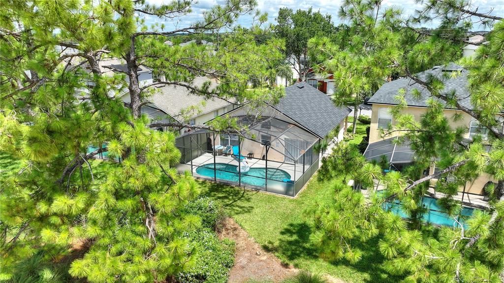 An aerial view shows three houses with screened-in swimming pools surrounded by pine trees — 2960 KOKOMO LOOP, HAINES CITY, FL