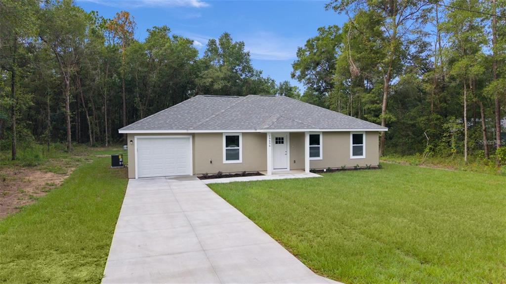 A single-story house with a tan exterior, gray roof, and a concrete driveway — 106 SEQUOIA TRAIL, OCKLAWAHA, FL