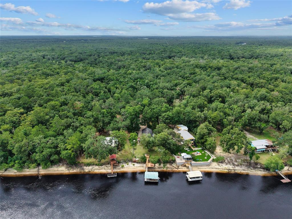 An aerial view shows several houses along a riverbank surrounded by a dense forest — 2159 NW 82ND TERRACE, BELL, FL