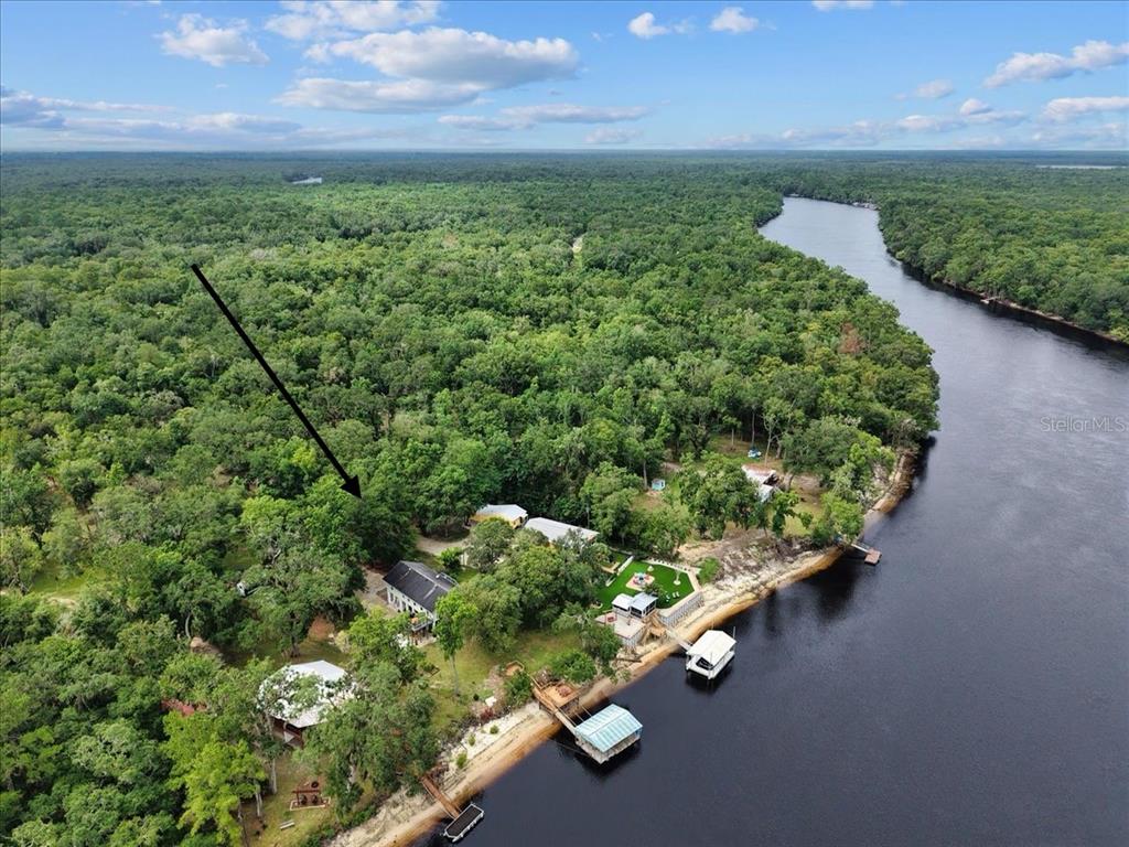 An aerial view shows a house nestled in a dense forest along a riverbank — 2159 NW 82ND TERRACE, BELL, FL