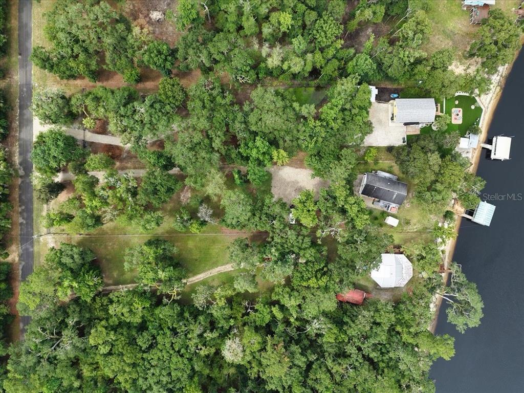 An aerial view shows three houses nestled among trees along a waterfront with private docks — 2159 NW 82ND TERRACE, BELL, FL