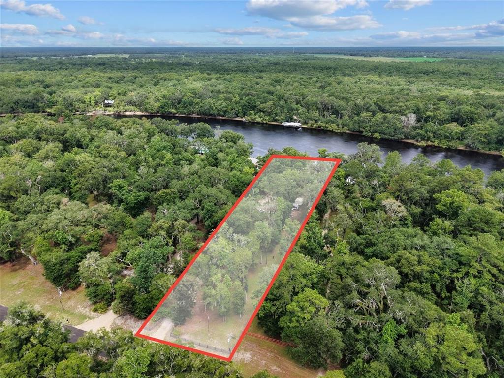 An aerial view shows a rectangular, tree-covered lot bordering a river — 2159 NW 82ND TERRACE, BELL, FL
