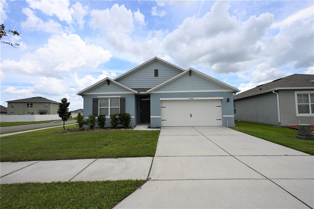 A single-story house with blue siding, a two-car garage, and a concrete driveway — 2548 RYLAND FALLS DRIVE, LAKELAND, FL