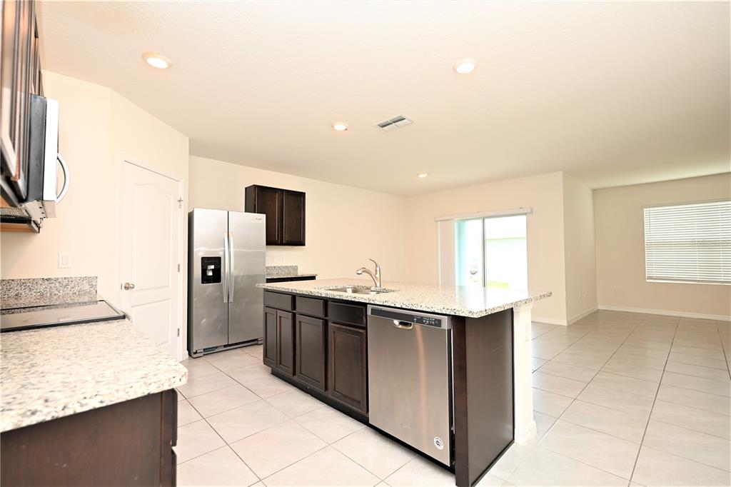 A kitchen with dark wood cabinets, granite countertops, stainless steel appliances, and tile flooring — 2548 RYLAND FALLS DRIVE, LAKELAND, FL