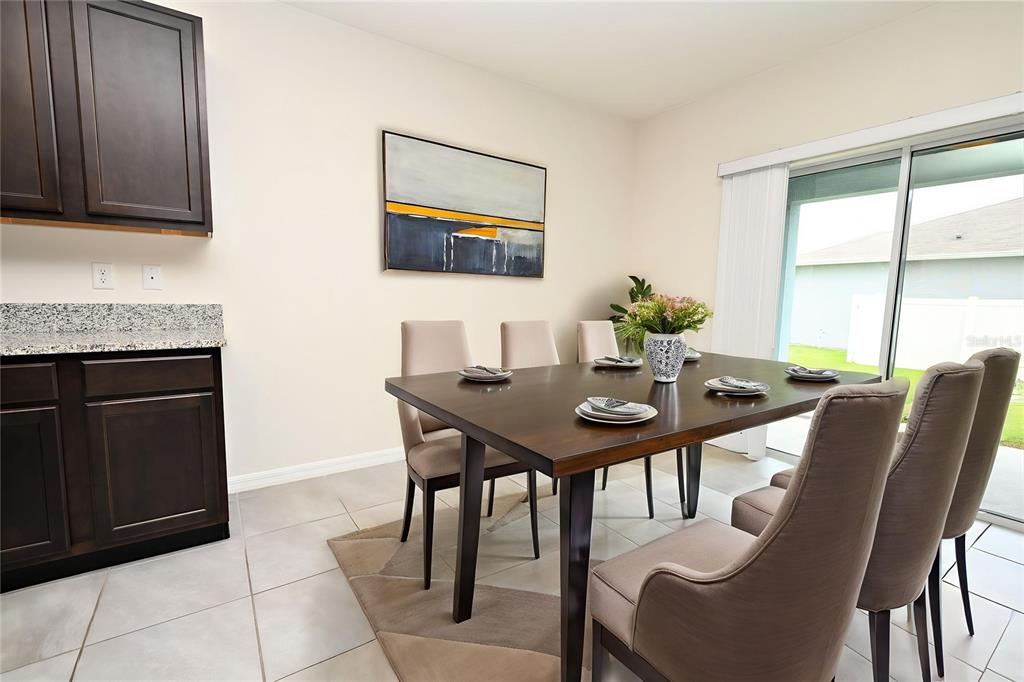 A dining area features a dark wood table, upholstered chairs, tile flooring, and sliding glass doors — 2548 RYLAND FALLS DRIVE, LAKELAND, FL
