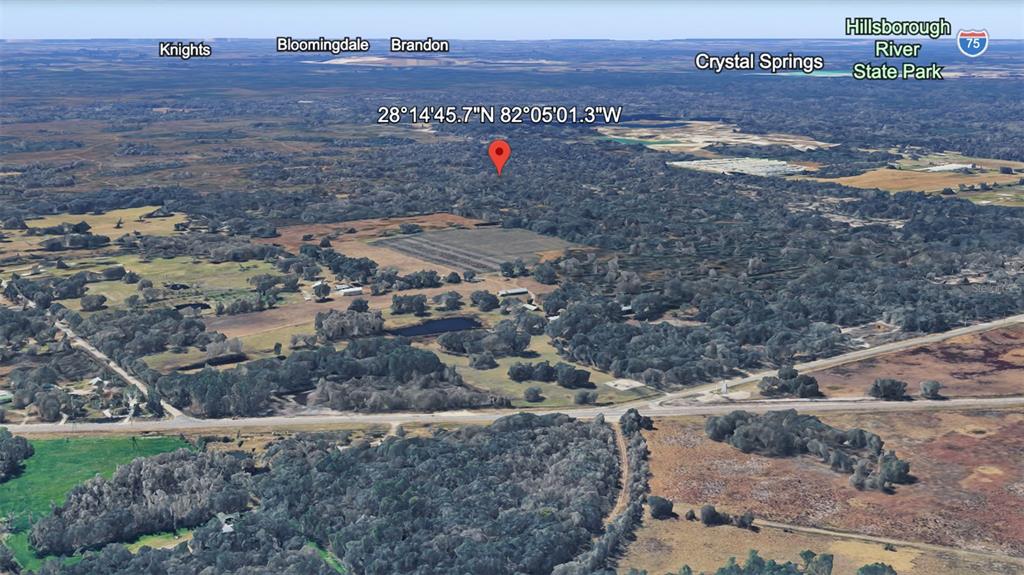 An aerial map view showing a rural landscape with trees, fields, and a red location pin — UNKNOWN, KATHLEEN, FL