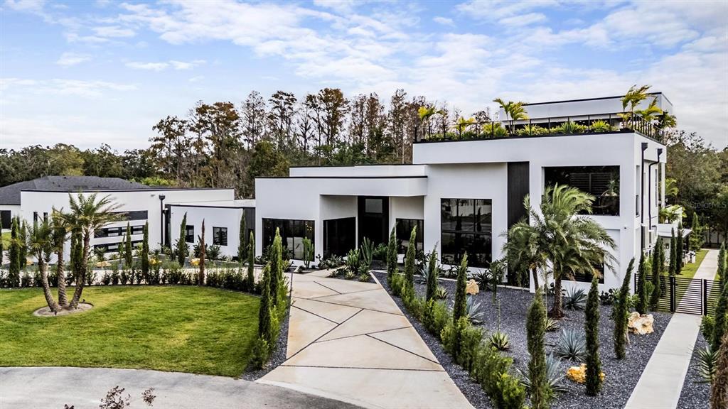 A modern white multi-story house with a geometric concrete driveway and landscaped front yard — 309 GRANDE GROVE COURT, LUTZ, FL