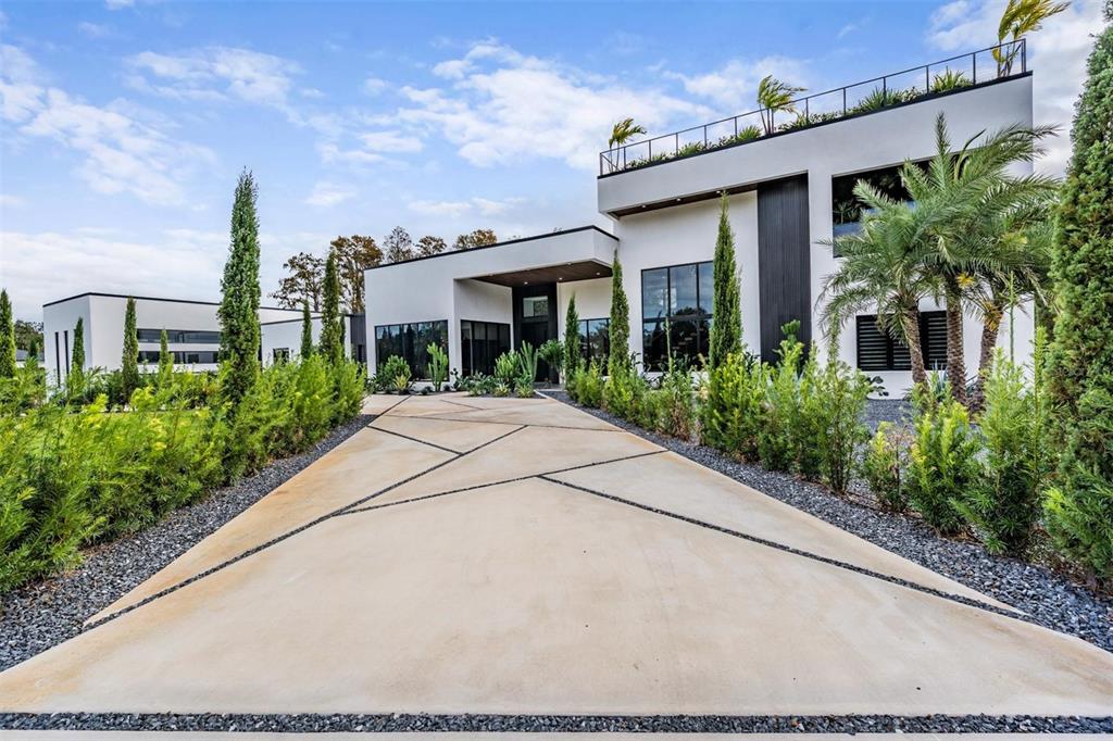 A modern white house with a geometric concrete driveway and landscaped garden under a blue sky — 309 GRANDE GROVE COURT, LUTZ, FL