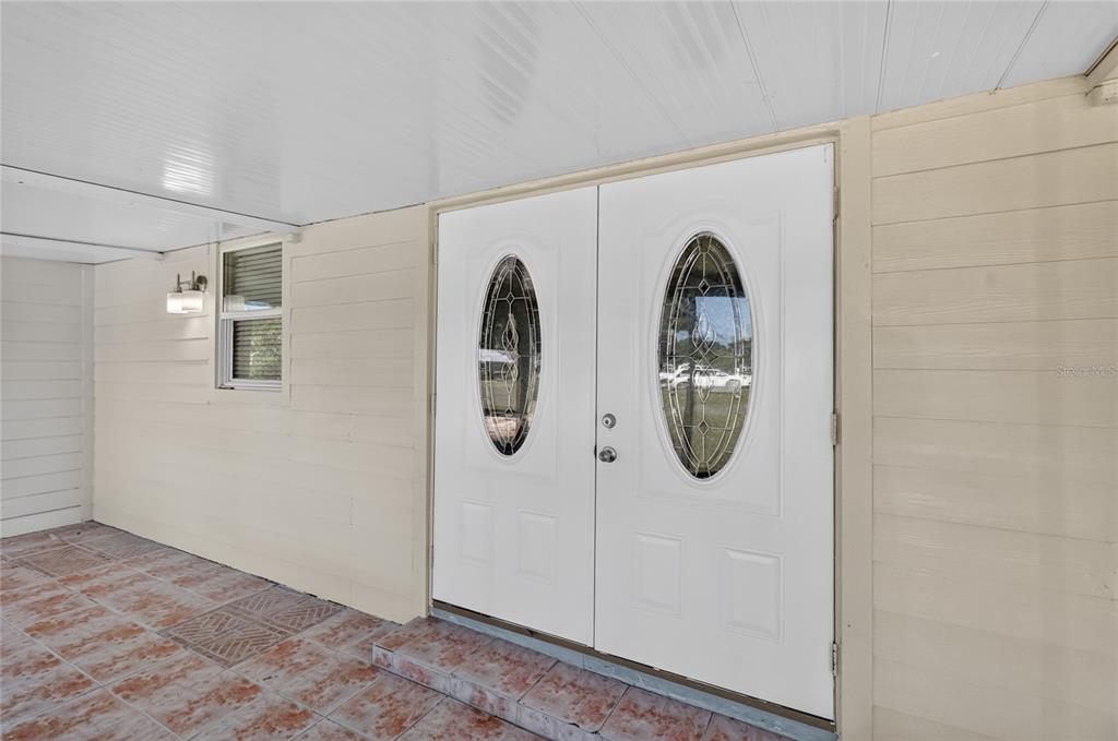 A covered porch features tiled flooring and a white double door with oval glass inserts — 3104 STEWART STREET, LAKELAND, FL