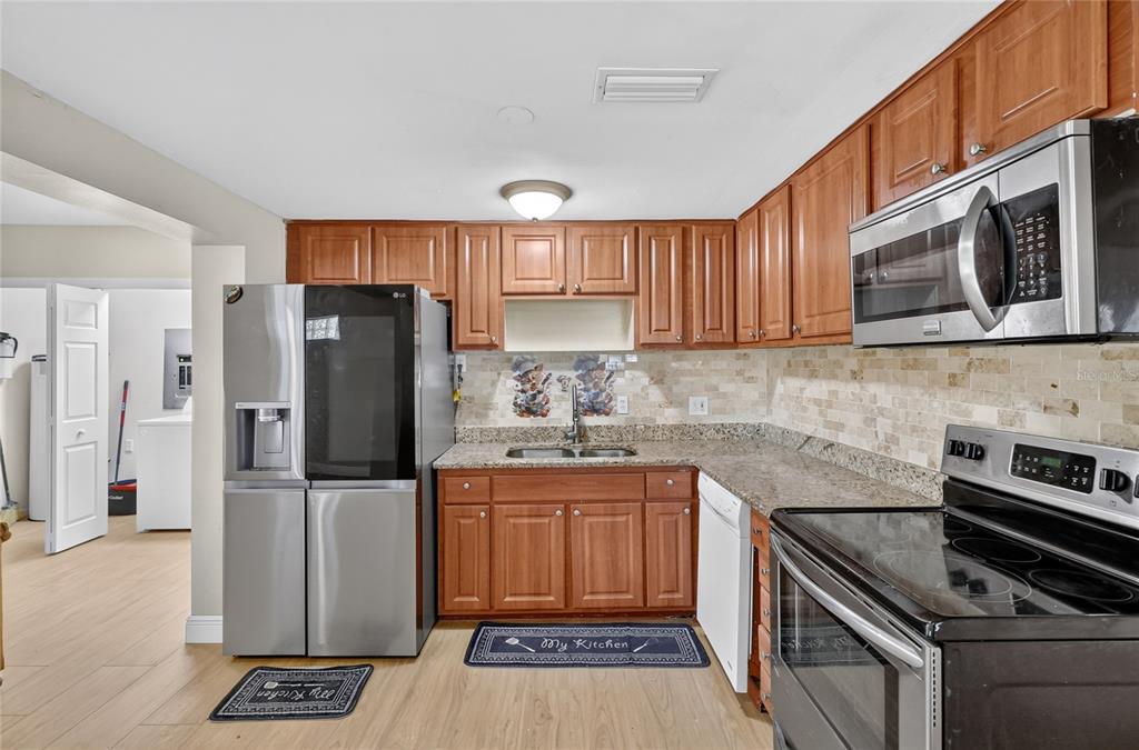 A kitchen with wood cabinets, stainless steel appliances, granite countertops, and a tiled backsplash — 3104 STEWART STREET, LAKELAND, FL