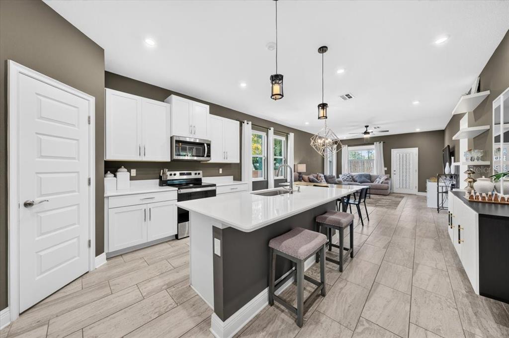 A modern kitchen with white cabinets, a quartz island, and gray tile flooring — 1821 27TH STREET S, ST PETERSBURG, FL