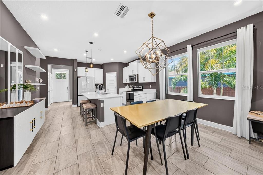 A modern kitchen and dining area with dark walls, white cabinetry, and a gold chandelier — 1821 27TH STREET S, ST PETERSBURG, FL