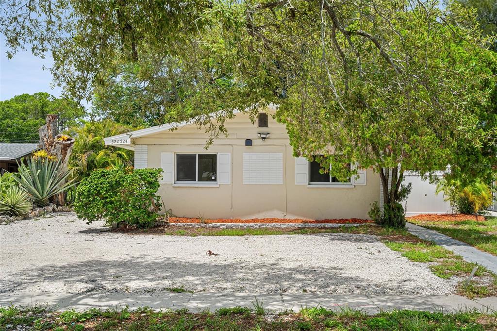 A single-story house with a gravel driveway, white shutters, and a large tree in front — 522 FLORIDA AVENUE, CLEARWATER, FL