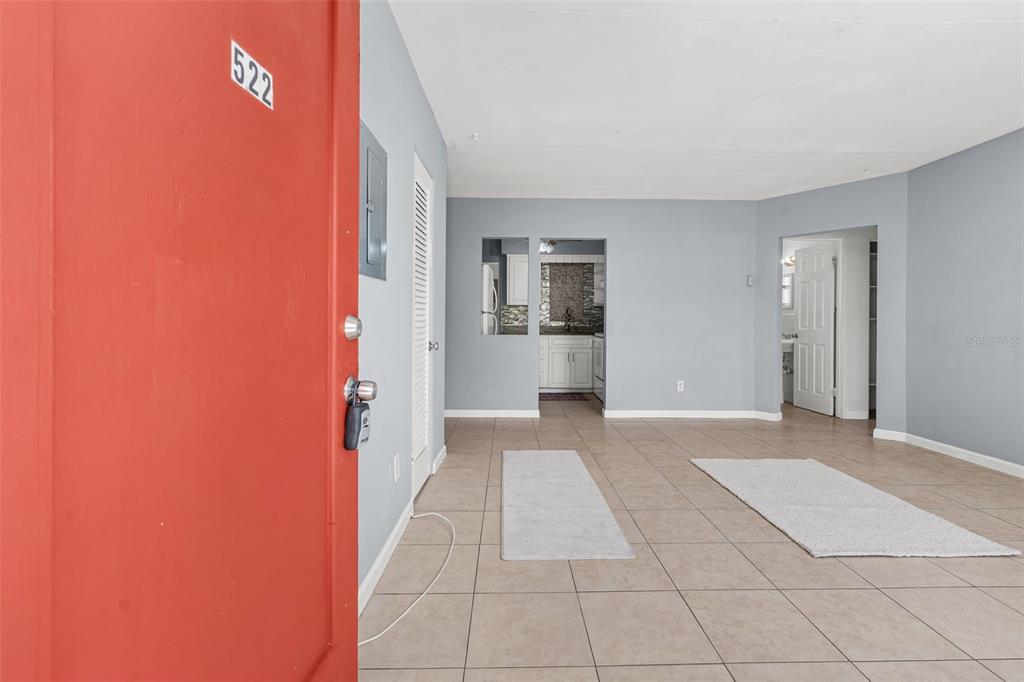 An open-concept living area with light gray walls, tile flooring, and a view into the kitchen — 522 FLORIDA AVENUE, CLEARWATER, FL