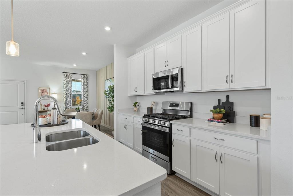 A modern kitchen features white cabinets, stainless steel appliances, and a large quartz-topped island — 118 ANCHOR LINE DRIVE, APOLLO BEACH, FL