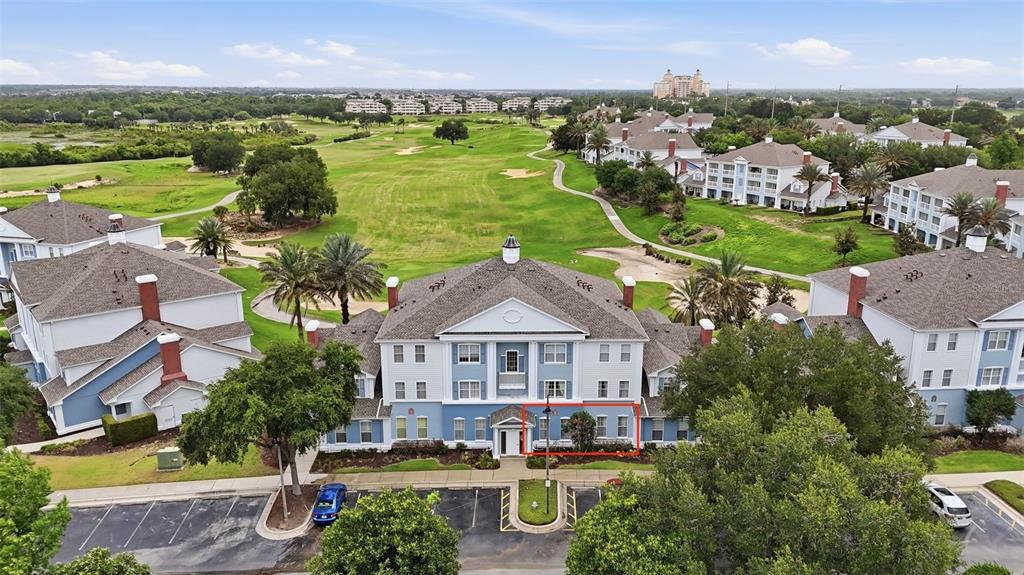 An aerial view shows multi-story apartment buildings situated along a green golf course — 7673 HERITAGE CROSSING WAY UNIT 102, REUNION, FL