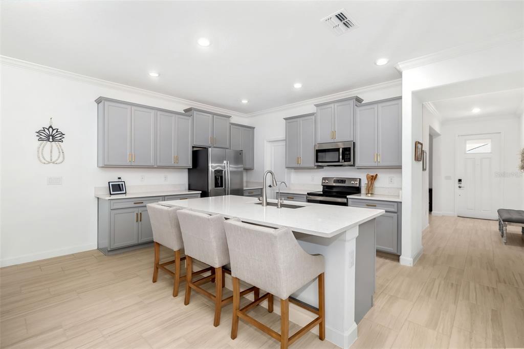 A kitchen features gray cabinets, white countertops, a central island with bar stools, and flooring — 14281 17TH COURT E, PARRISH, FL