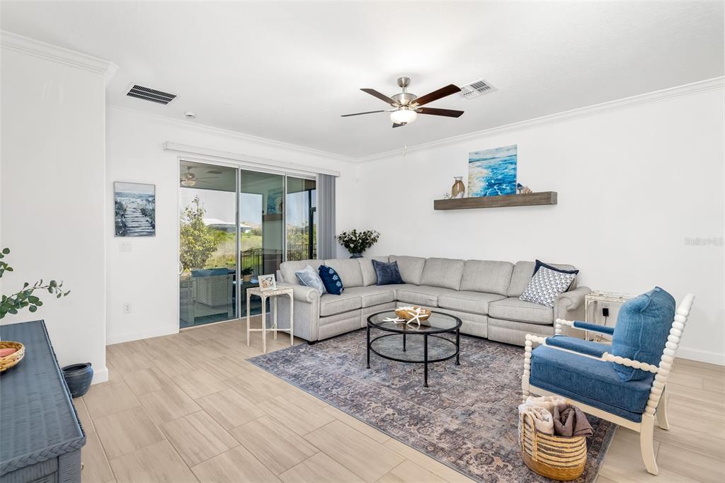 A living room features a sectional sofa, blue armchair, area rug, and sliding glass doors — 14281 17TH COURT E, PARRISH, FL