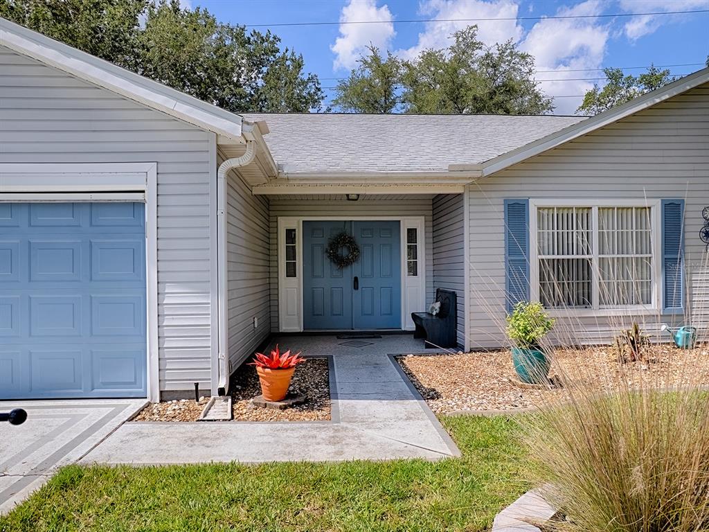 A light gray house features a blue garage door, blue double front doors, and blue shutters — 4438 RIVER RIDGE DRIVE, LEESBURG, FL