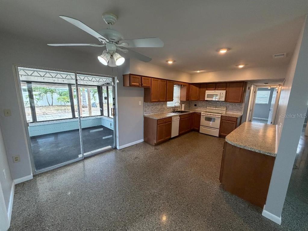 A kitchen with wood cabinets, white appliances, and a sliding glass door to a patio — 6017 43RD AVENUE N, ST PETERSBURG, FL