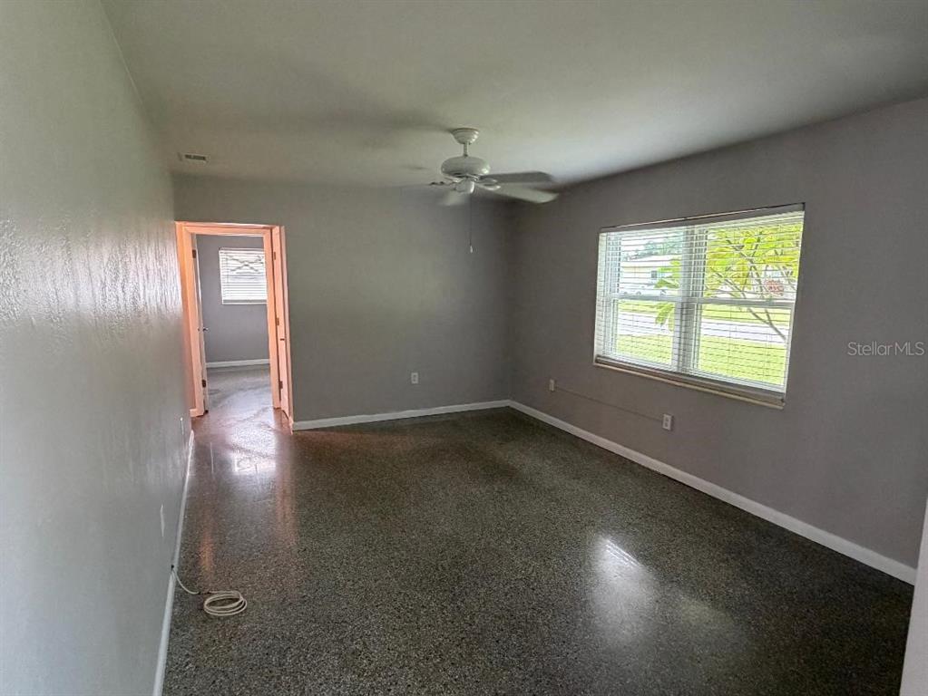 An empty room with gray walls, a ceiling fan, and speckled flooring — 6017 43RD AVENUE N, ST PETERSBURG, FL