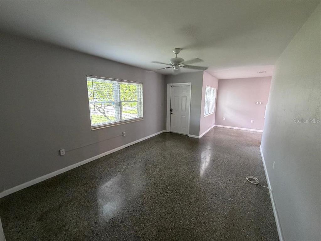 An empty room features gray walls, a ceiling fan, and polished concrete flooring — 6017 43RD AVENUE N, ST PETERSBURG, FL