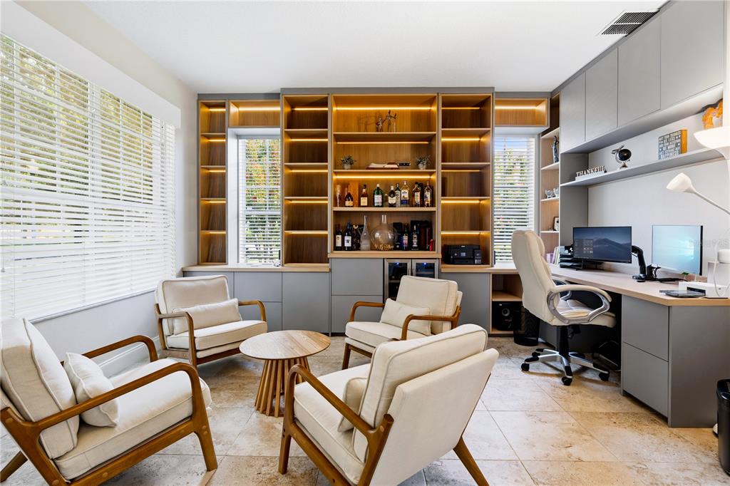 A home office features built-in shelving, a desk, and a seating area with four chairs — 10355 EMERALD WOODS AVENUE, ORLANDO, FL