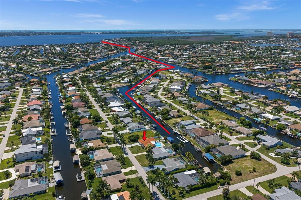 An aerial view shows a waterfront residential neighborhood with a red arrow marking a house — 4914 SORRENTO COURT, CAPE CORAL, FL