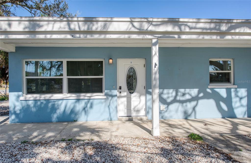 The exterior of a light blue house features a white front door and a concrete porch — 717 E GULF BOULEVARD UNIT 2, INDIAN ROCKS BEACH, FL