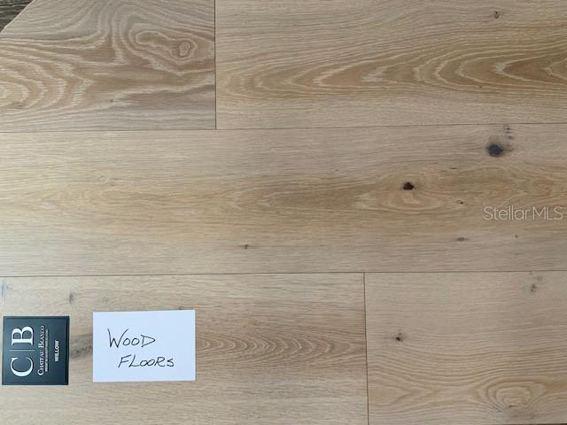 A close-up view of light-toned wood flooring planks with a product label and note — 1509 FLOWER DRIVE, SARASOTA, FL