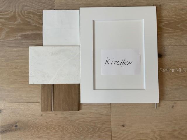A kitchen design sample board features a white cabinet door, marble-look tiles, and wood flooring — 1509 FLOWER DRIVE, SARASOTA, FL