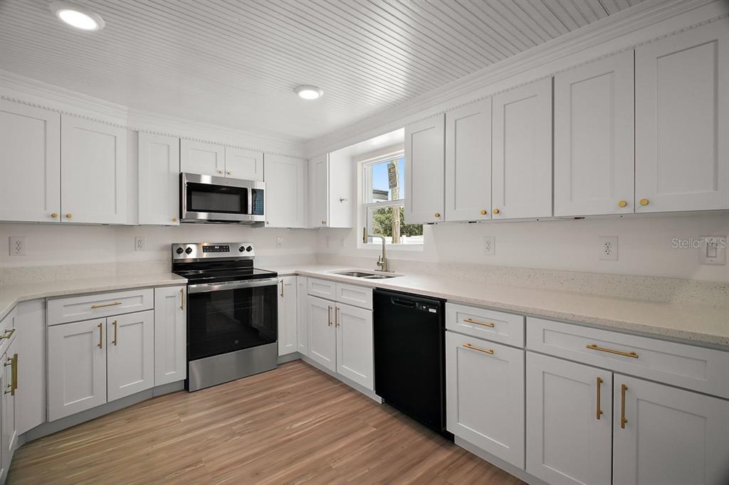 The exterior of a house features a red front door, two windows, and a concrete patio — 1103 MALCOM ROAD, OCOEE, FL