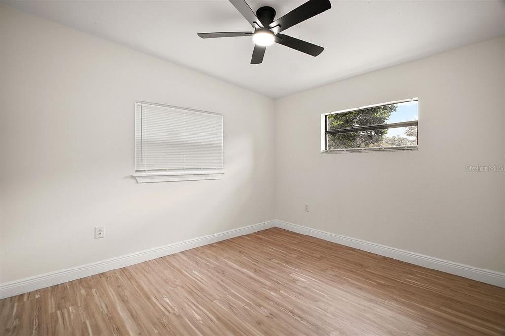 A concrete patio with a yellow table and chairs sits in a grassy backyard — 1103 MALCOM ROAD, OCOEE, FL