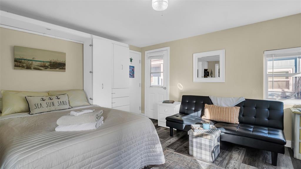 A bedroom features a bed, a black futon, white storage cabinets, and light-colored walls — 483 E SHORE DRIVE UNIT D3, CLEARWATER BEACH, FL