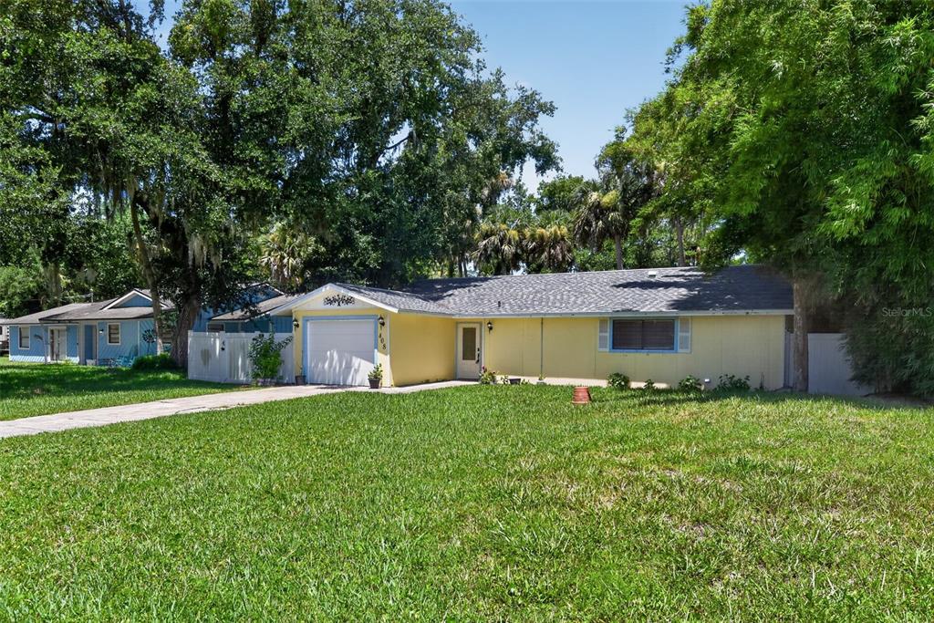 A yellow single-story house with a white garage door and a large front lawn — 408 PALM AVENUE, ORMOND BEACH, FL