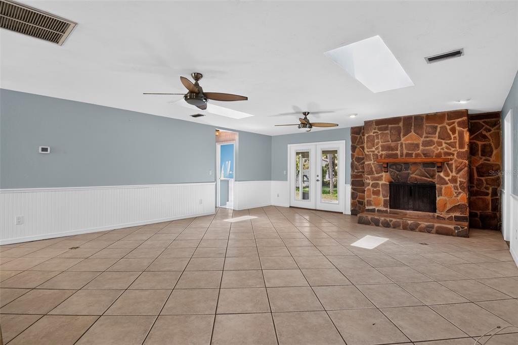 A spacious living room features tile flooring, a stone fireplace, and two ceiling fans — 408 PALM AVENUE, ORMOND BEACH, FL