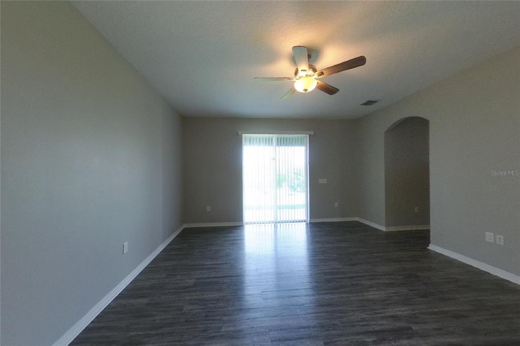 An empty living room features gray wood-look flooring, light walls, and a ceiling fan — 226 BLACKSTONE CREEK ROAD, GROVELAND, FL