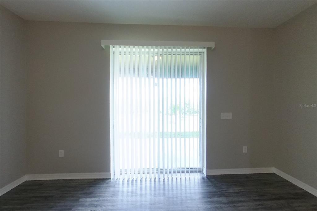 A room with gray walls, dark wood-look flooring, and a sliding glass door with blinds — 226 BLACKSTONE CREEK ROAD, GROVELAND, FL