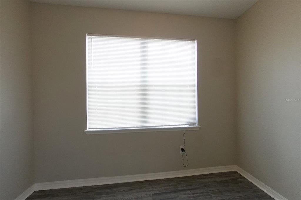 A room with light gray walls, a window with white blinds, and gray wood-look flooring — 226 BLACKSTONE CREEK ROAD, GROVELAND, FL