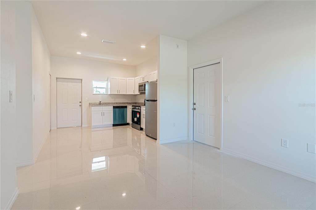 A kitchen with white cabinets and stainless steel appliances opens into a tiled living area — 753 PACIFIC STREET, LAKE PLACID, FL
