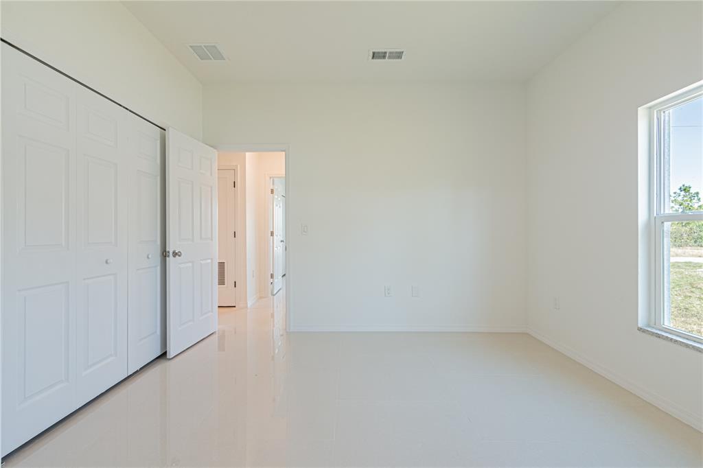 An empty bedroom features white walls, light tile flooring, a closet, and a single window — 753 PACIFIC STREET, LAKE PLACID, FL
