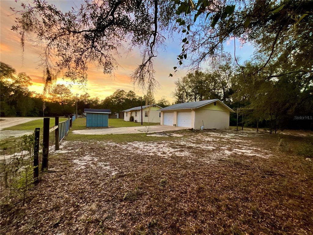 A detached two-car garage and a small shed sit on a grassy lot at sunset — 600 WAKULLA STREET, FLORAHOME, FL