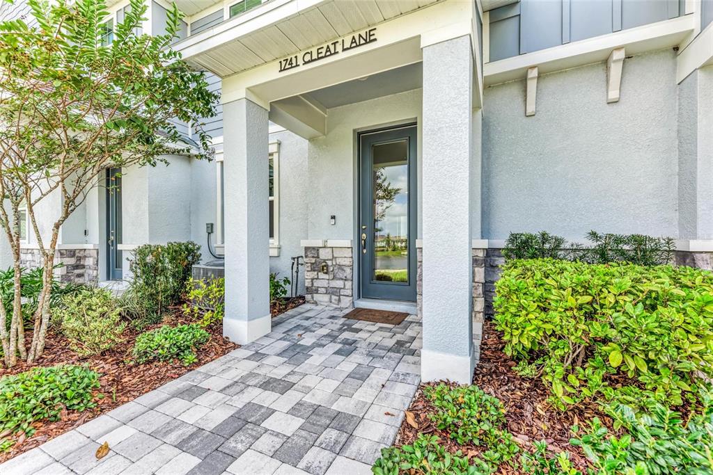 A paved walkway leads to the front entrance of a house with stone accents — 1741 CLEAT LANE, SARASOTA, FL
