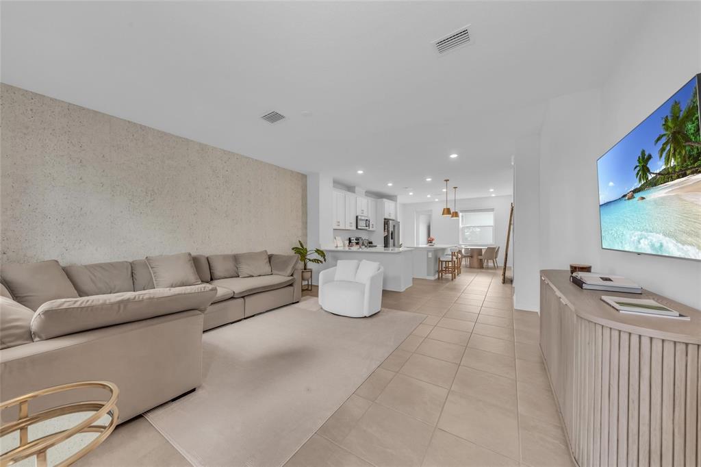 A living room with a beige sofa, white armchair, and a television faces a kitchen — 1741 CLEAT LANE, SARASOTA, FL