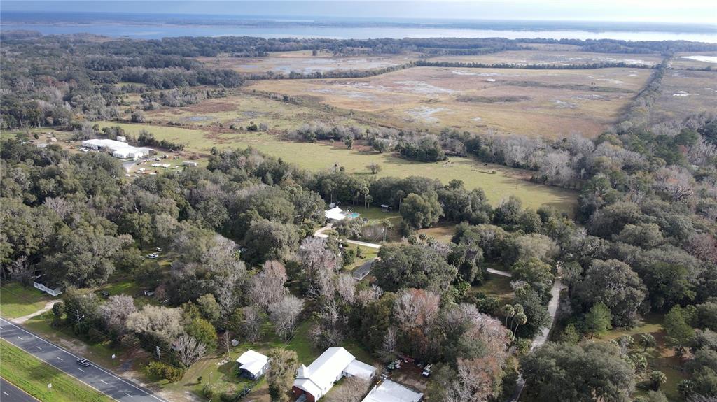 An aerial view shows a rural property with a church, trees, and open fields — 5725 NW 210TH STREET, MICANOPY, FL