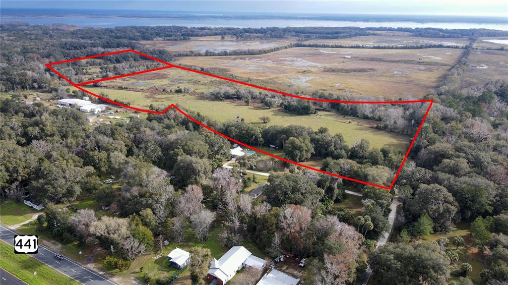An aerial view shows a large, grassy parcel of land outlined in red near a highway — 5725 NW 210TH STREET, MICANOPY, FL