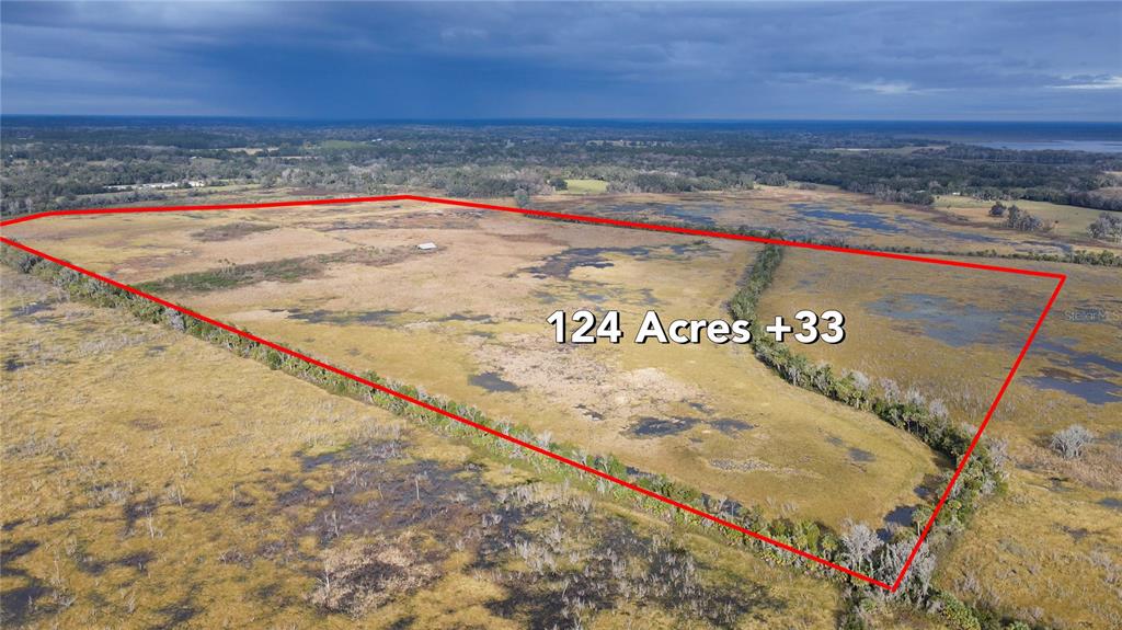 An aerial view shows a large, open tract of land outlined in red — 5725 NW 210TH STREET, MICANOPY, FL